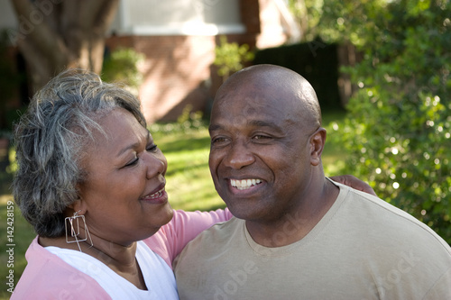 Mature African American couple laughing and hugging.