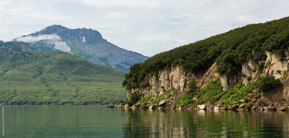 Beautiful coast of Kurile Lake is reflected in the water.