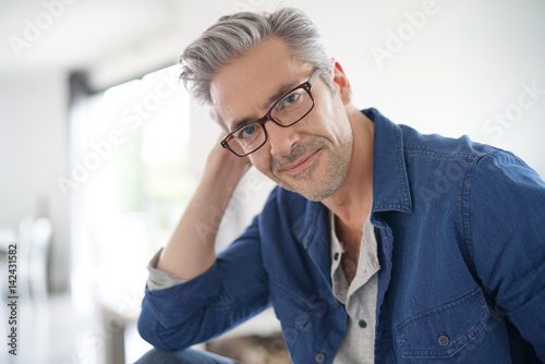 Portrait of mature man with eyeglasses sitting on sofa