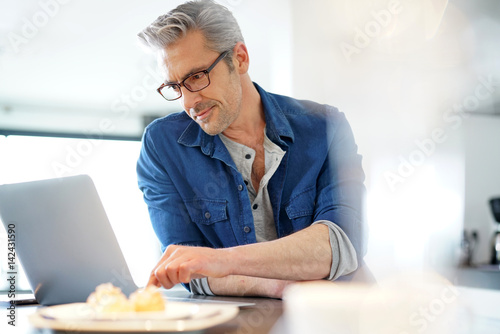 Handsome 45-year-old man at home connected on laptop