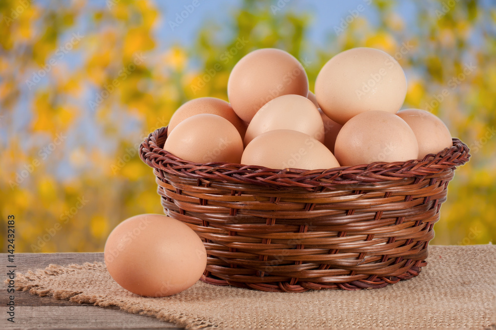 eggs in a wicker basket on a wooden board with blurred garden background