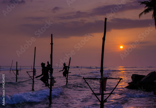 Silhouettes of the traditional Sri Lankan stilt fishermen at the sunset in Weligama, Sri Lanka. Stilt fishing is a method of fishing unique to the island country of Sri Lanka photo