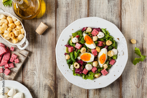 Delicious Italian salad with salami, egg, crostini and mozzarella. photo