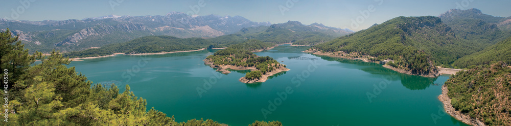 Turkey . Panorama . Huge deep lake in the mountains . Rocky coast with pine trees growing on them . Clean water, allowing breeding trout.