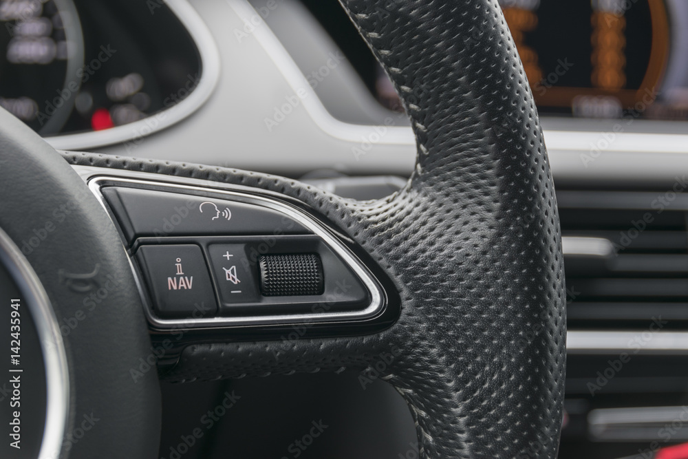 media control buttons on the steering wheel in black leather modern car interior	