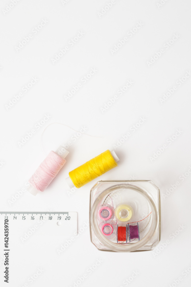 Colored thread coils on white background, sewing tools Colored thread coils on white background, sewing tools