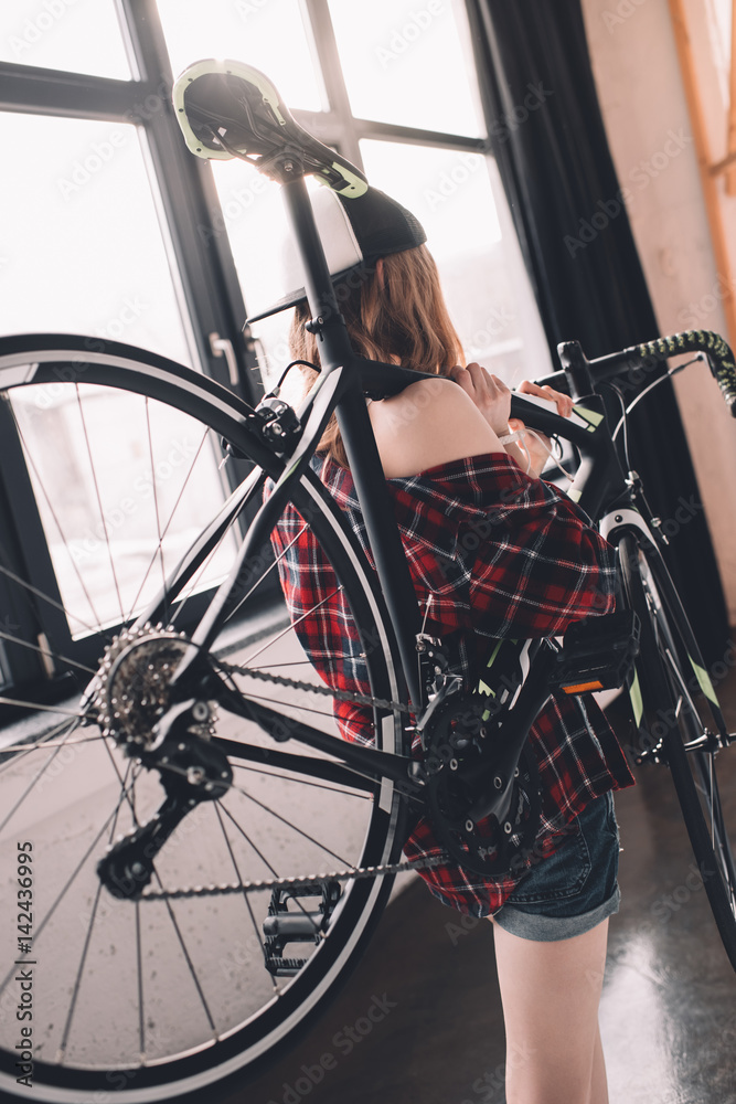 back view of stylish woman holding sports bicycle back view of stylish woman holding sports bicycle