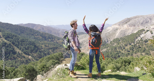 Back view of loving couple having fun while hiking in mountains with beautiful view on background. 