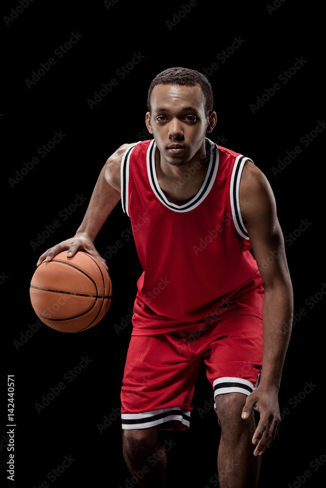 Young sportsman in uniform playing basketball with ball on black Young sportsman in uniform playing basketball with ball on black