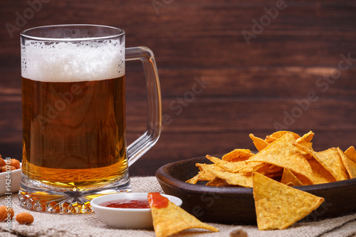 Glass of beer. Nachos chips. Tortilla snack. Mexican salsa nuts. Appetizer with sweet salsa or chilli sauce. Mug or pint of ale. On rustic wooden background.