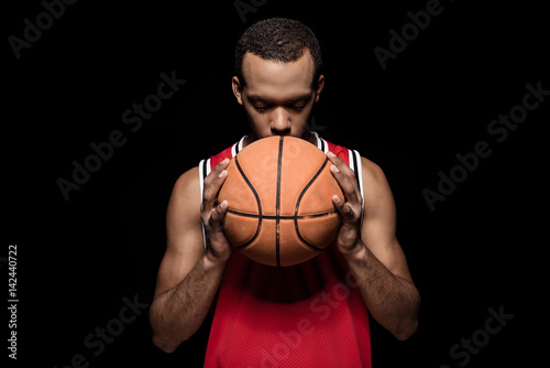 African american basketball player posing with ball on black © LIGHTFIELD STUDIOS