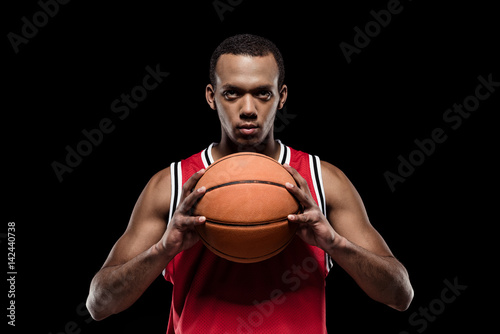 African american basketball player posing with ball on black © LIGHTFIELD STUDIOS