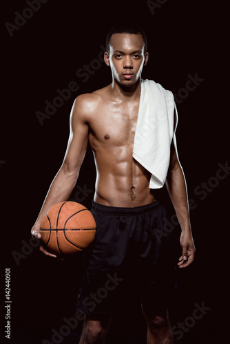 African american basketball player posing with ball and towel on black