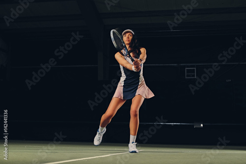Female tennis player in a jump on a tennis court.