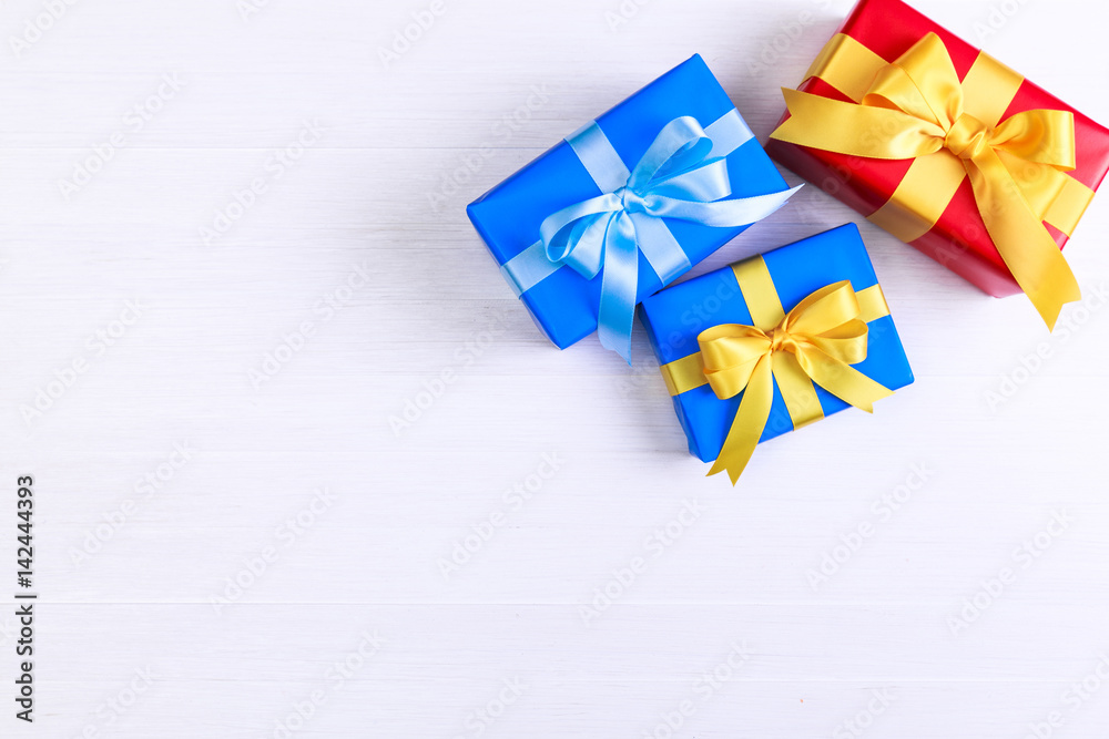 Gift boxes with bow. Presents wrapped with paper and ribbons. Christmas or birthday packages. Celebration design. On white wooden table. Gift boxes with bow. Presents wrapped with paper and ribbons. Christmas or birthday packages. Celebration design. On white wooden table.