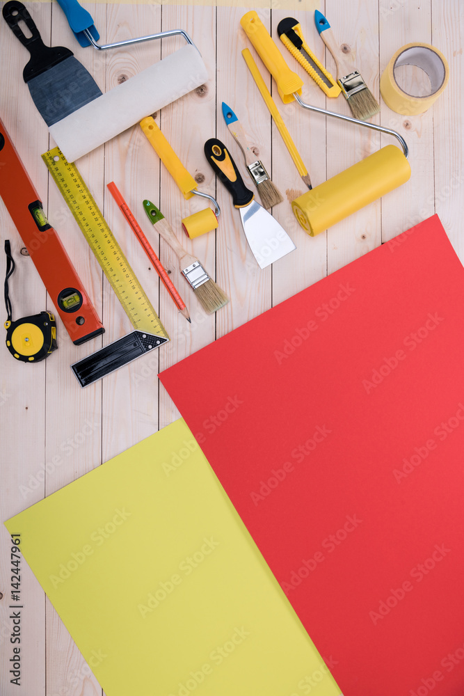 Top view of set of construction tools and colored paper on wooden table Top view of set of construction tools and colored paper on wooden table