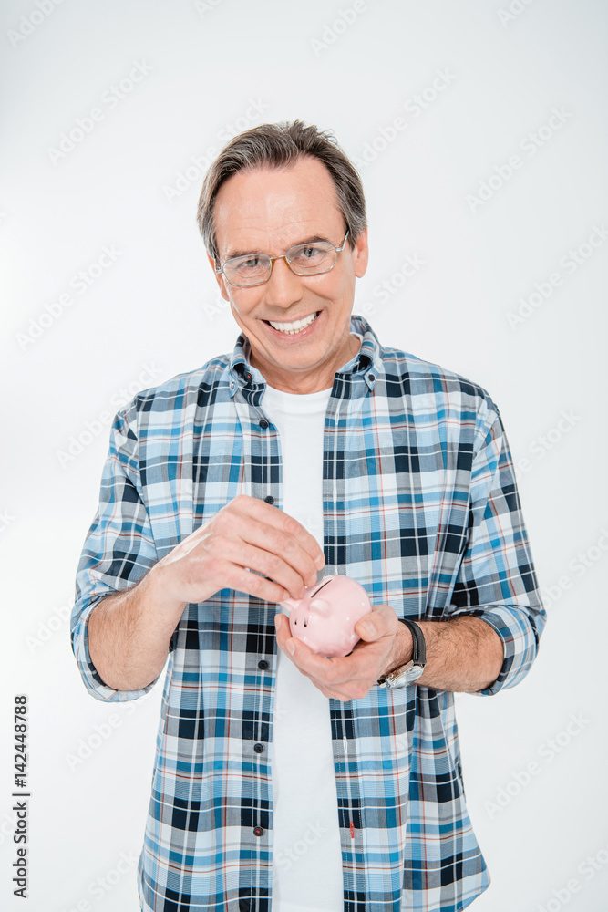 Front view of happy man putting coin in piggy bank on white Front view of happy man putting coin in piggy bank on white