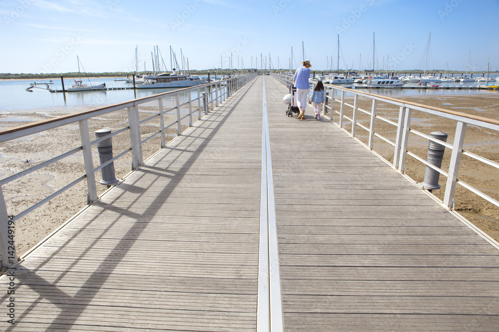 Fototapeta premium People walking by footbridge at marina, Huelva, Spain