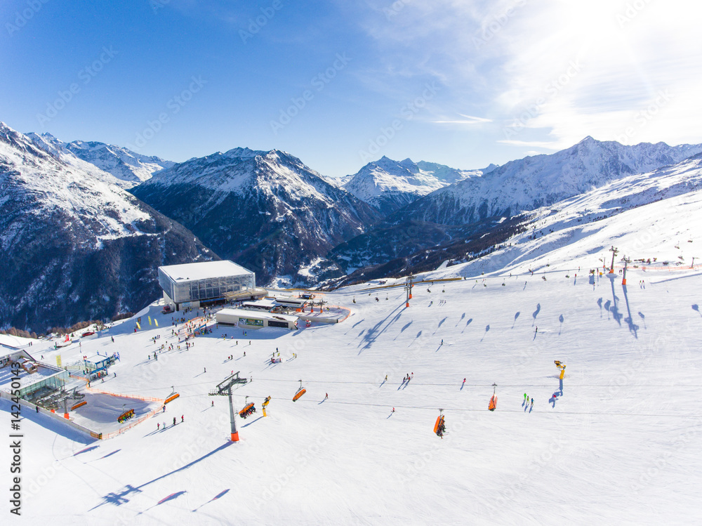 Ski resort in the Alps with ski lift and people skiing on the slope