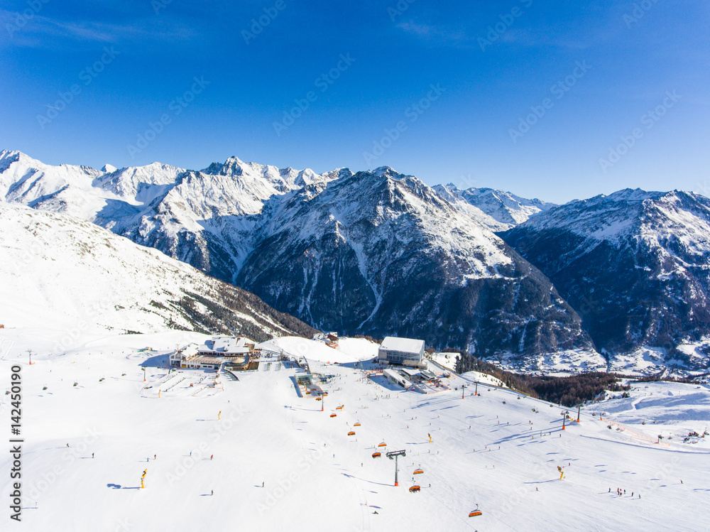 Aerial view of ski resort in the Alps with ski lift and people skiing on the slope