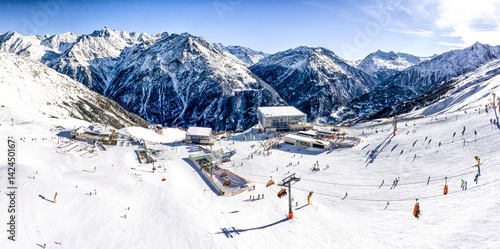 Panoramic aerial view of ski resort in the Alps with ski lift and people skiing on the slope photo