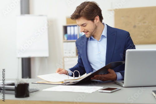 geschäftsmann sitzt am schreibtisch und schaut in einen aktenordner photo