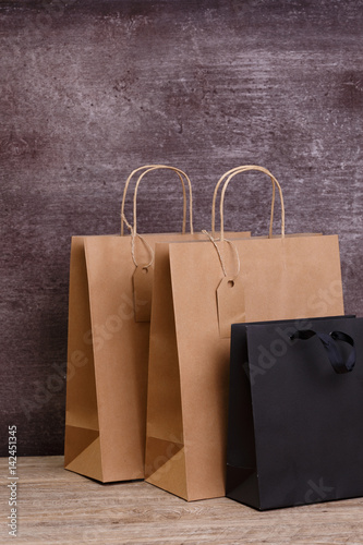 Mockup of blank shopping bags. Brown and black craft packages. Concept for sales or discounts. Recycled paper. Wooden rustic board.