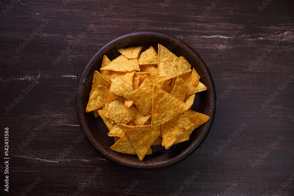 Nachos chips. Delicious salty tortilla snack on rustic plate. On wooden table background.