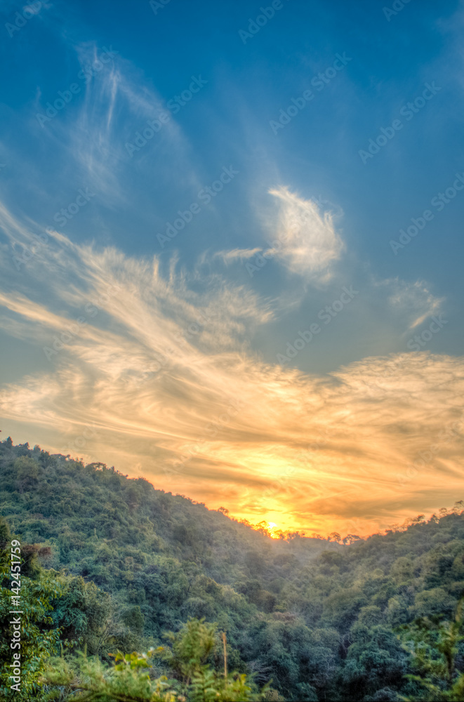 Mountain forest landscape under evening sky with clouds in sunlight. Majestic sunset in indian Himalaya mountains. HDR image.