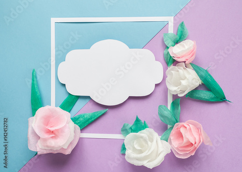 square frame with color paper flowers on the blue and violet background. Flat lay. Nature concept