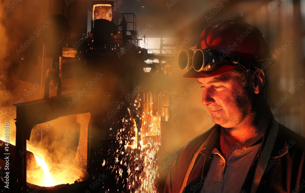 Hard work in the foundry, worker watching and controlling iron smelting in furnaces, too hot and smoky working environment Hard work in the foundry, worker watching and controlling iron smelting in furnaces, too hot and smoky working environment