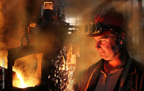 Hard work in the foundry, worker watching and controlling iron smelting in furnaces, too hot and smoky working environment