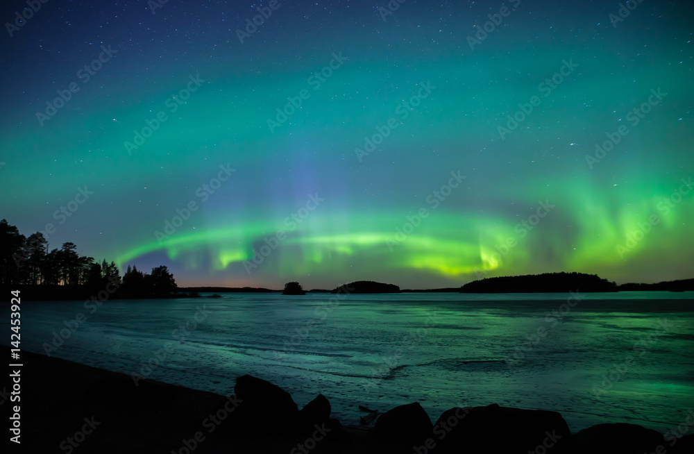 Northern lights dancing over frozen lake in spring