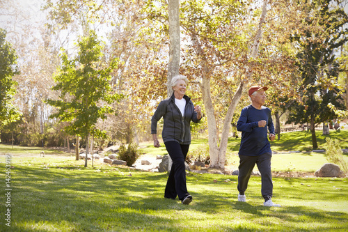 Side View Of Senior Couple Power Walking Through Park