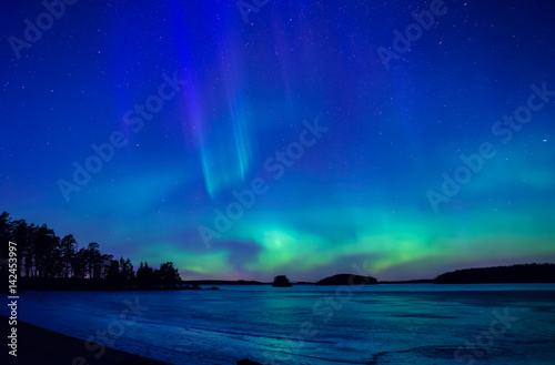 Northern lights dancing over frozen lake in spring © Conny Sjostrom