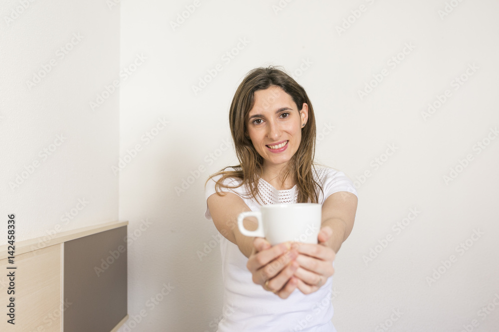 beautiful young woman holding a cup of coffee in her bedroom. sitting on bed and smiling. Home and lifestyle beautiful young woman holding a cup of coffee in her bedroom. sitting on bed and smiling. Home and lifestyle