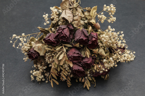 Verwelkter Brautstrauß mit roten Rose Jahre nach der Hochzeit auf grauem Schieferplate-Steintisch mit Textraum