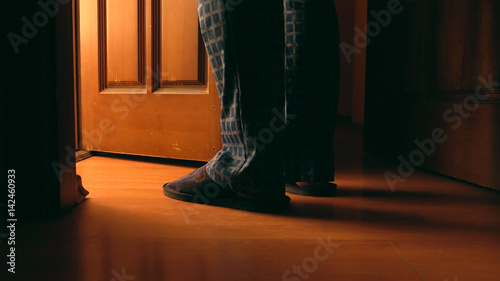 Adult man stands near door to a bathroom at the night