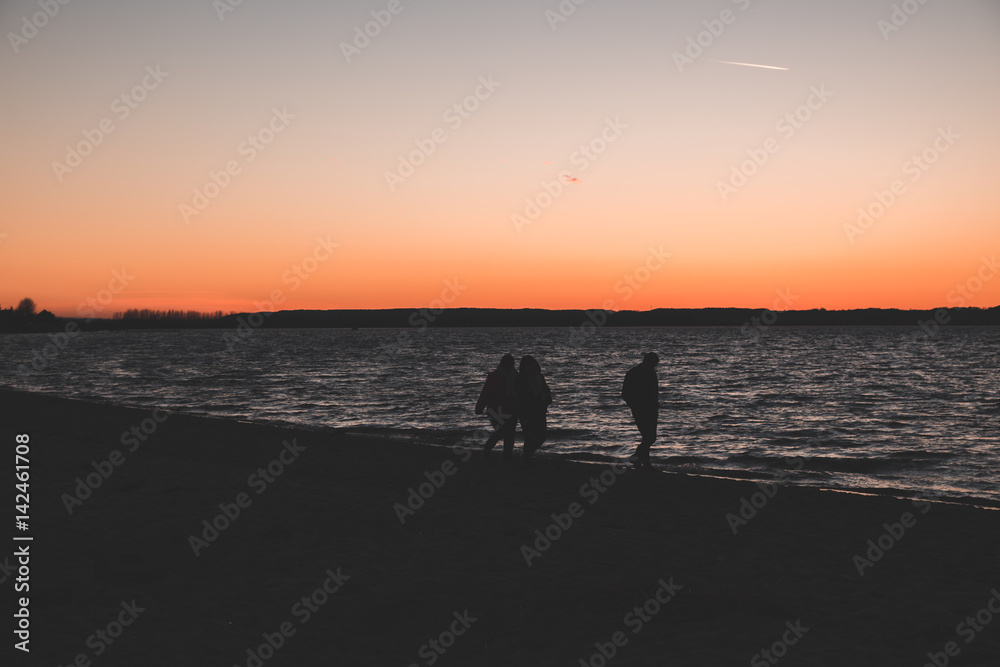 Silhouette of people walking on the beach