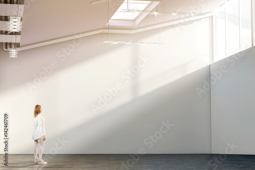 Woman walking near blank white wall mockup in modern gallery photo