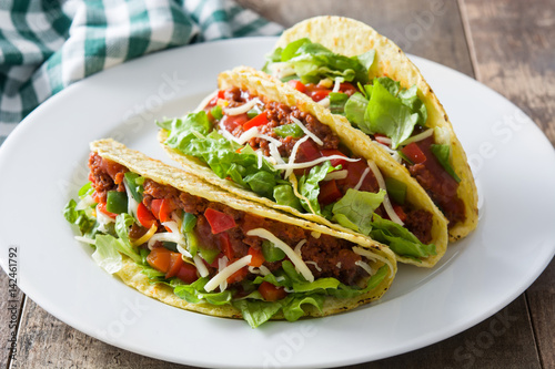 Traditional Mexican tacos with meat and vegetables on wooden background
