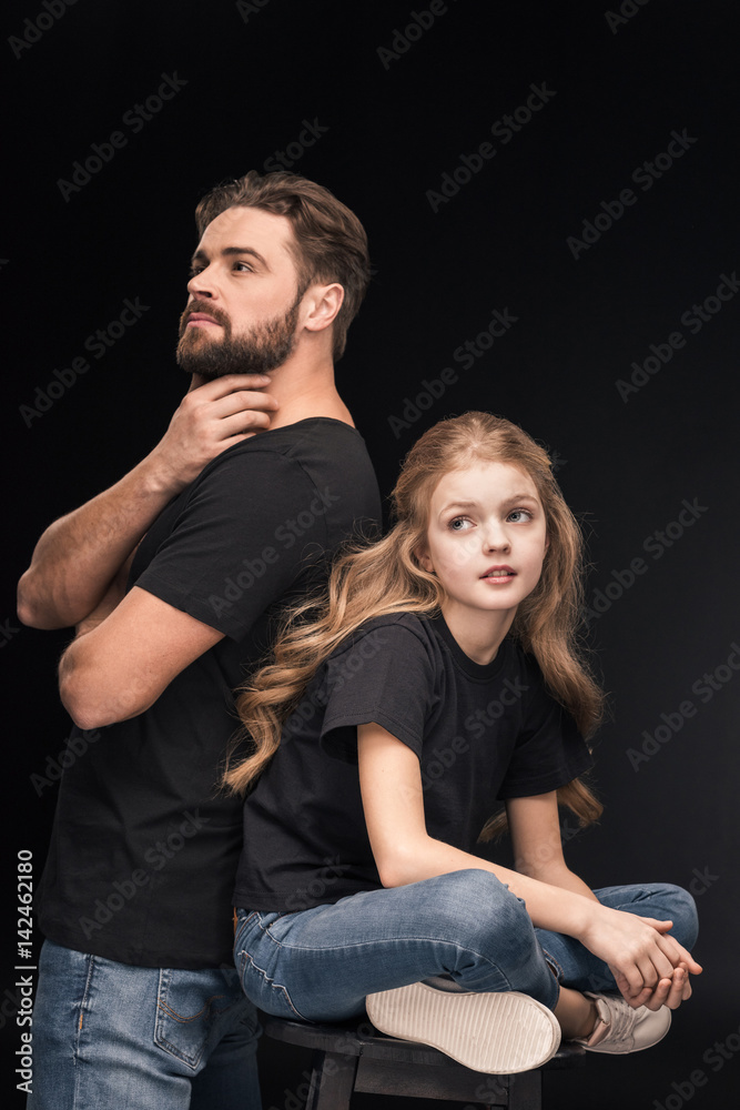 Fototapeta premium adorable pensive daughter and pensive father back to back on black