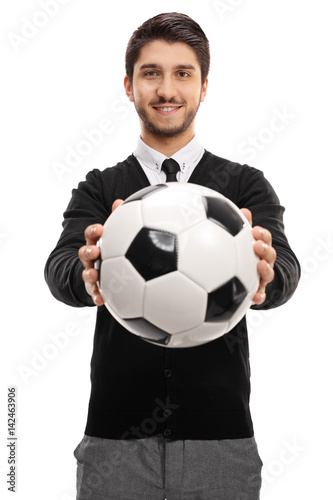 Young man handing a football towards the camera
