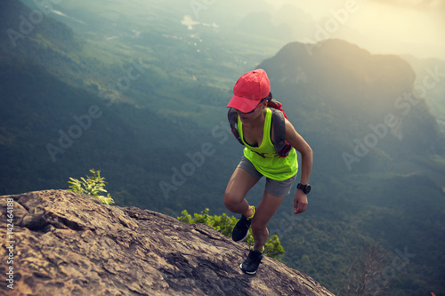 Young fitness woman trail runner running at mountain top