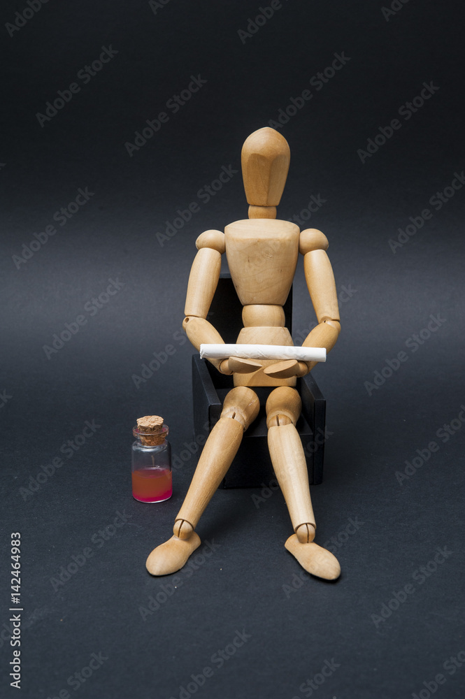 /Person represented by a wooden dummy sitting on an armchair and holding a cigarette with a bottle of alcoholic drink aside. /Person represented by a wooden dummy sitting on an armchair and holding a cigarette with a bottle of alcoholic drink aside.