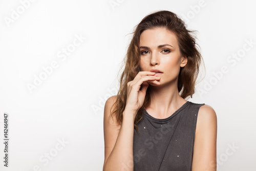 Cute stylish young woman with curly hair and hand near face on a white background