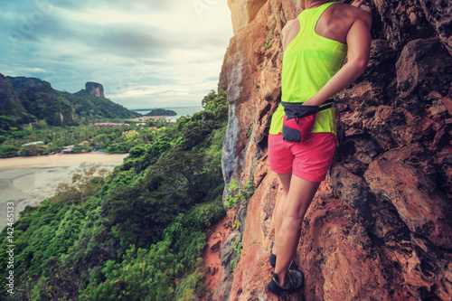 free solo woman rock climber climbing at seaside cliff