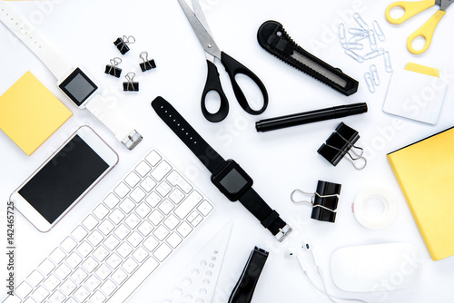 Flat lay of office supplies, keyboard, smartphone and smartwatches on white