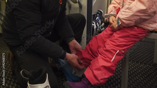 A father helping his daughter to put on her ski boots, 4K