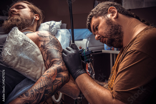 Tattooer create tattoo in tattoo parlor